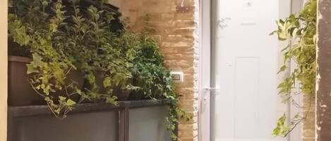 Una puerta con panel de vidrio esmerilado, una reja de metal y un muro de piedra.