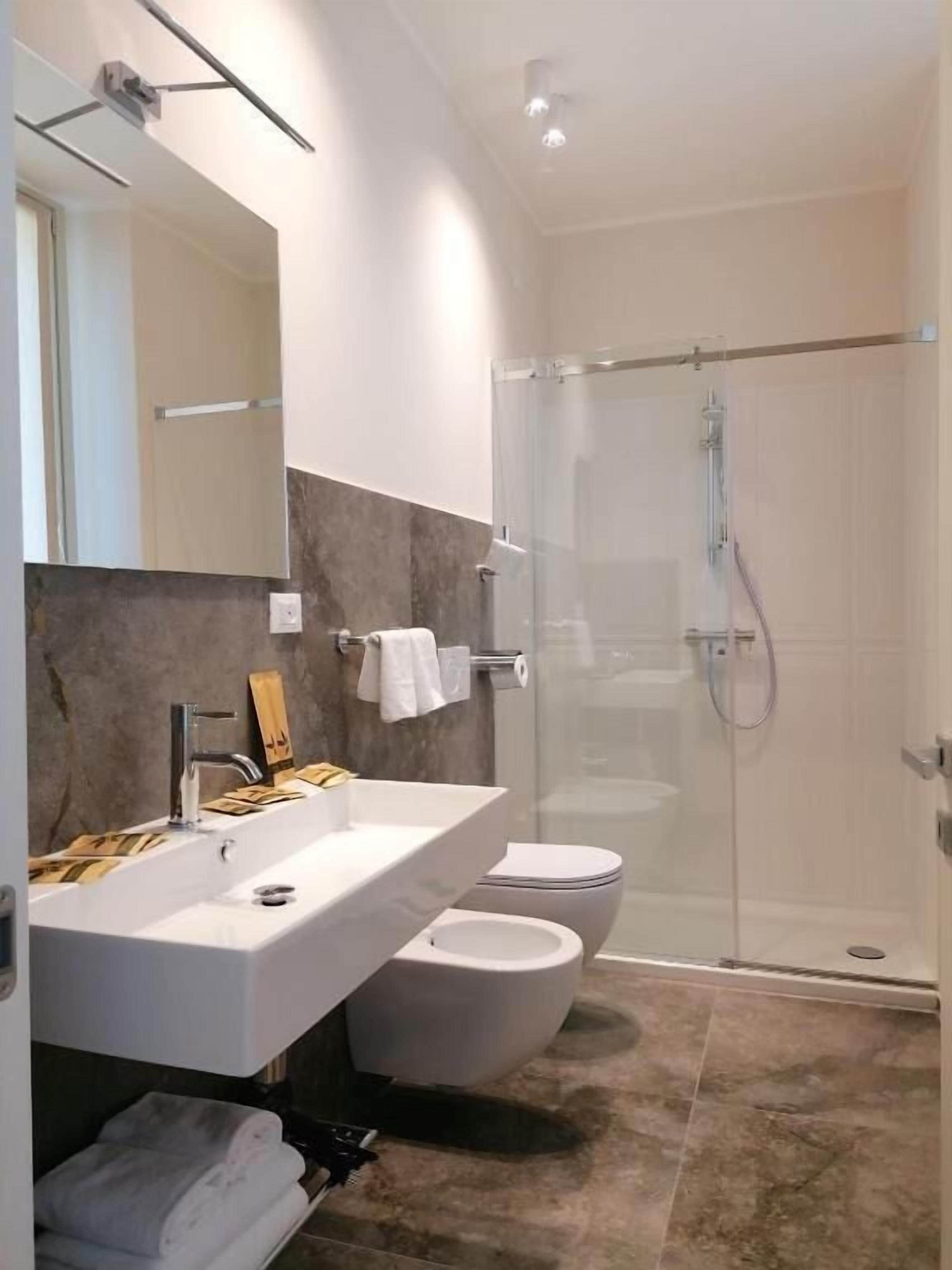 Ein modernes Badezimmer mit einer gläsernen Duschkabine, einem weißen Waschbecken und einer Toilette.