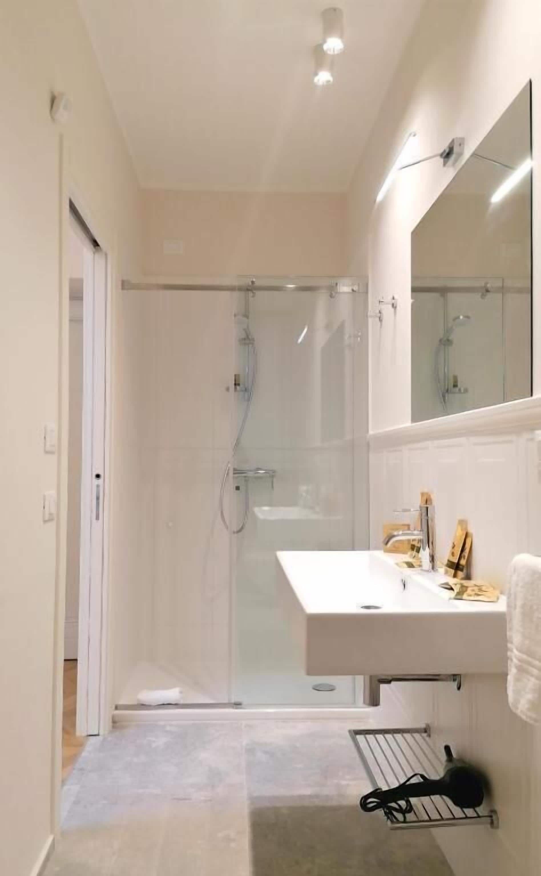 A modern bathroom with a glass-enclosed shower, a white sink, and a towel rack.