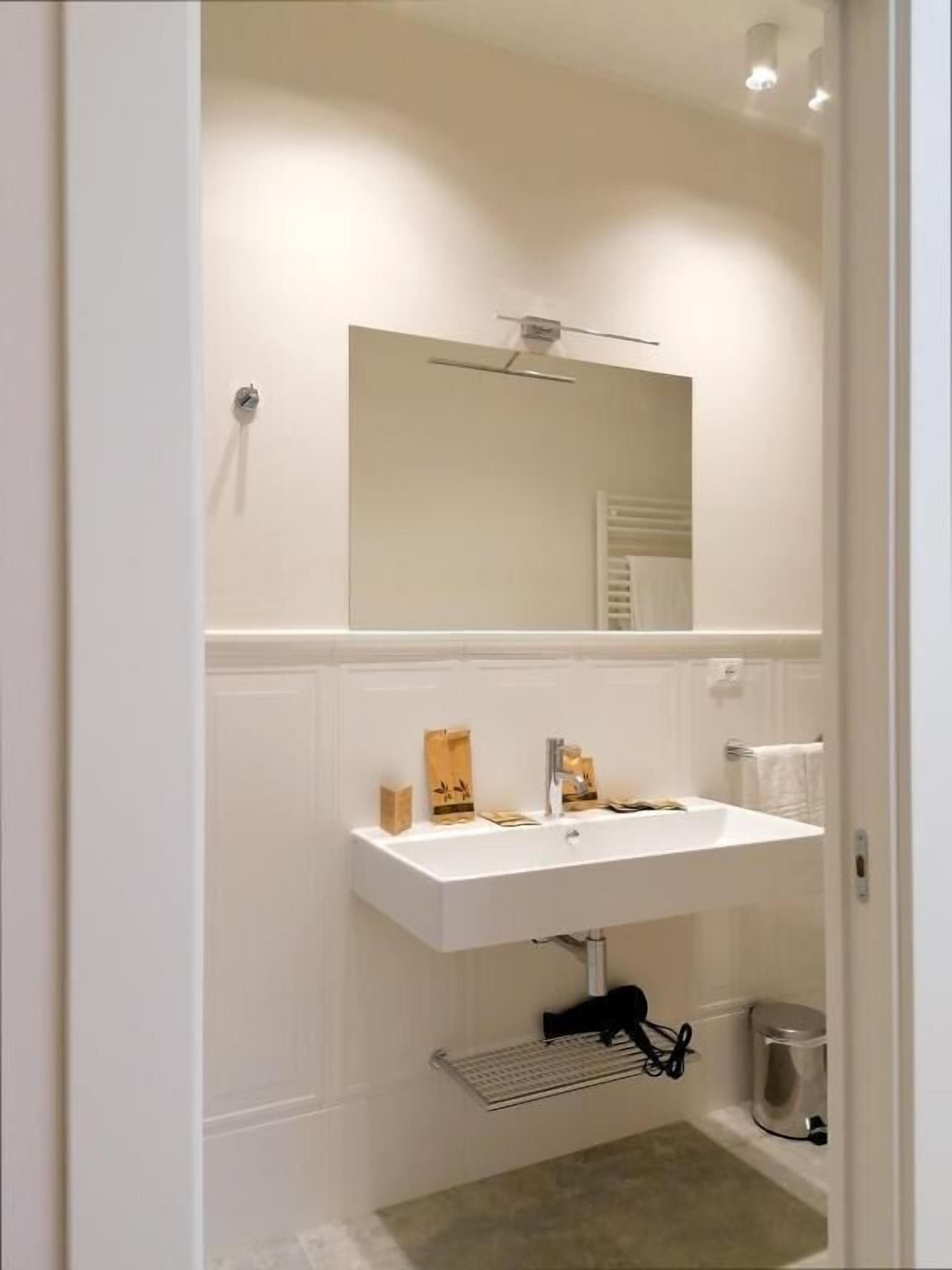 A bathroom with a white sink, mirror, and towel rack.