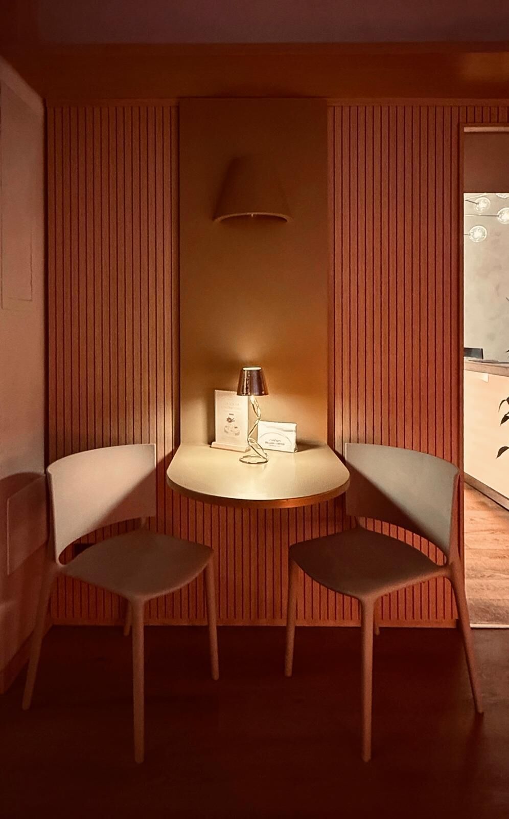 A room with two chairs and a table, a lamp, and a wall-mounted light fixture.