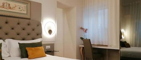 A hotel room with a large bed, a desk, and a mirror.