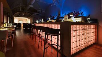 A bar area with wooden stools, a bar counter, and a variety of bottles.