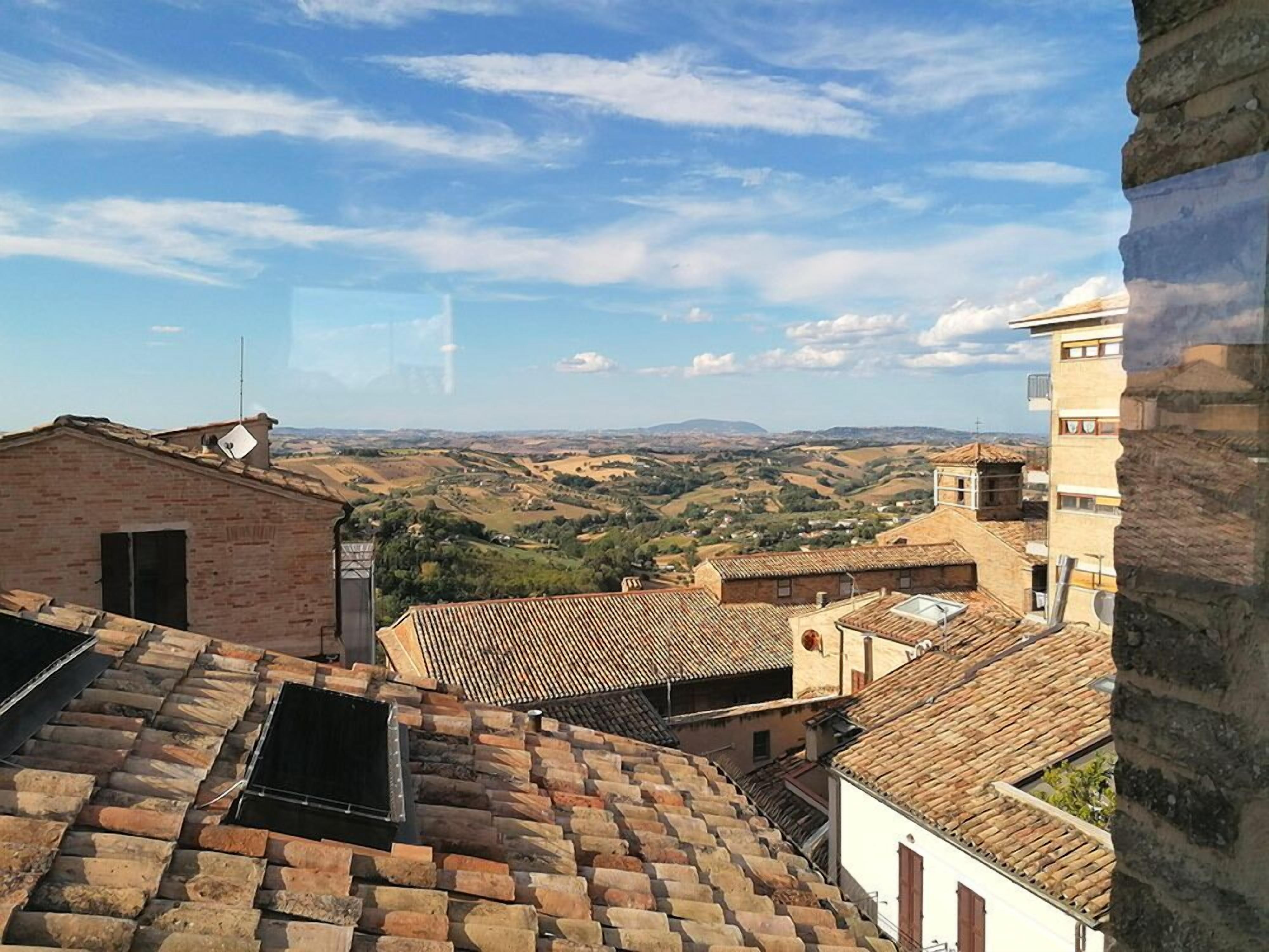 Vista de un pueblo con edificios de tejados de teja y cielo despejado.