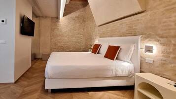 A bedroom with a bed, a television, and a wall-mounted light fixture.