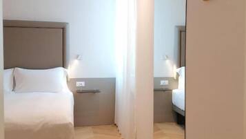 A hotel room with a bed, bedside table, and a mirror.