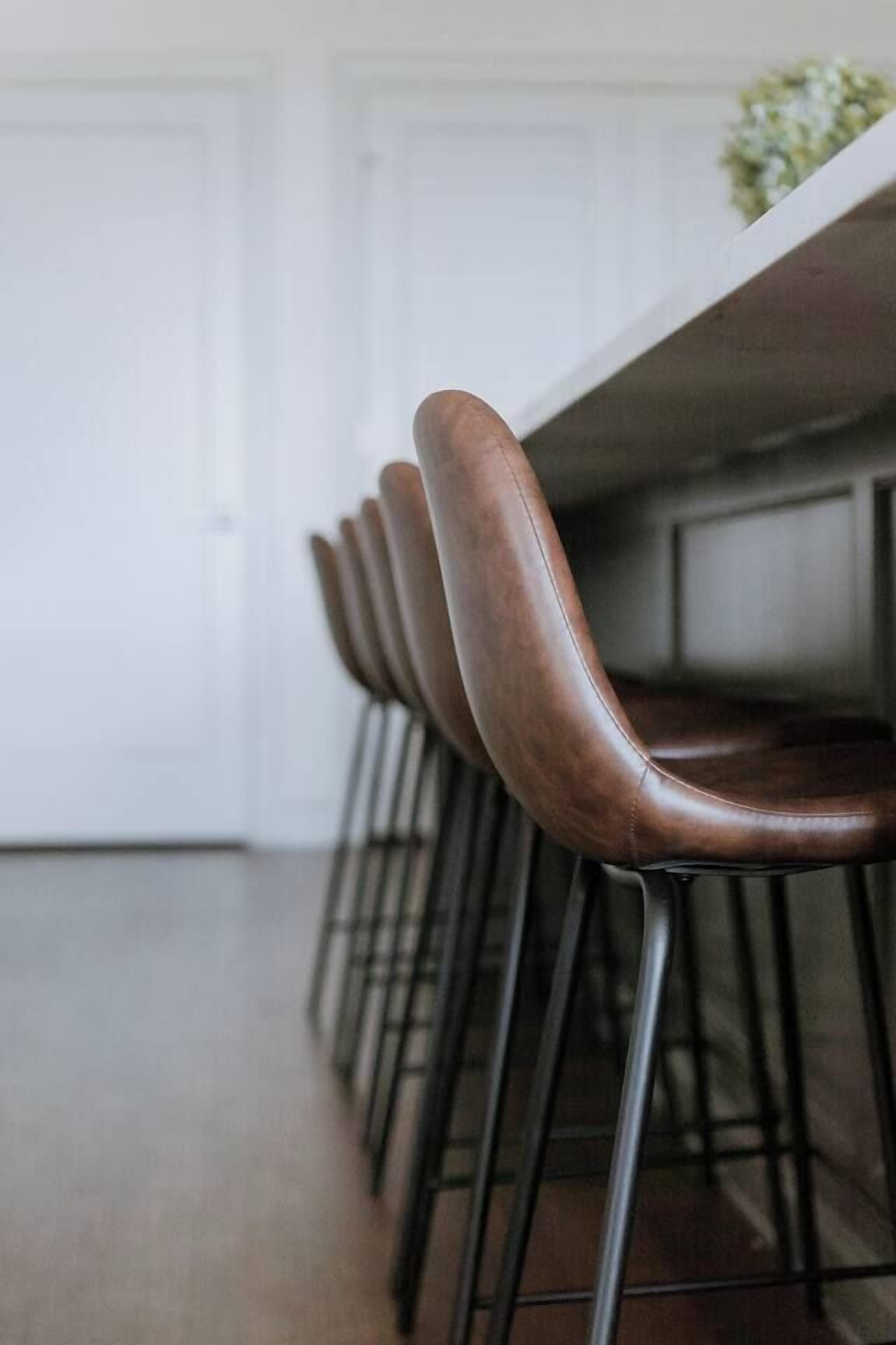 A row of bar stools with metal legs and a wooden seat, aligned along a white table.