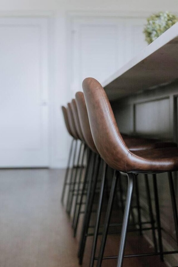 A row of bar stools with metal legs and a wooden seat, aligned along a white table.
