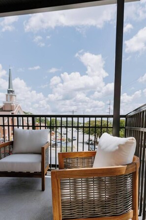 A balcony with wicker furniture and a view of a church.