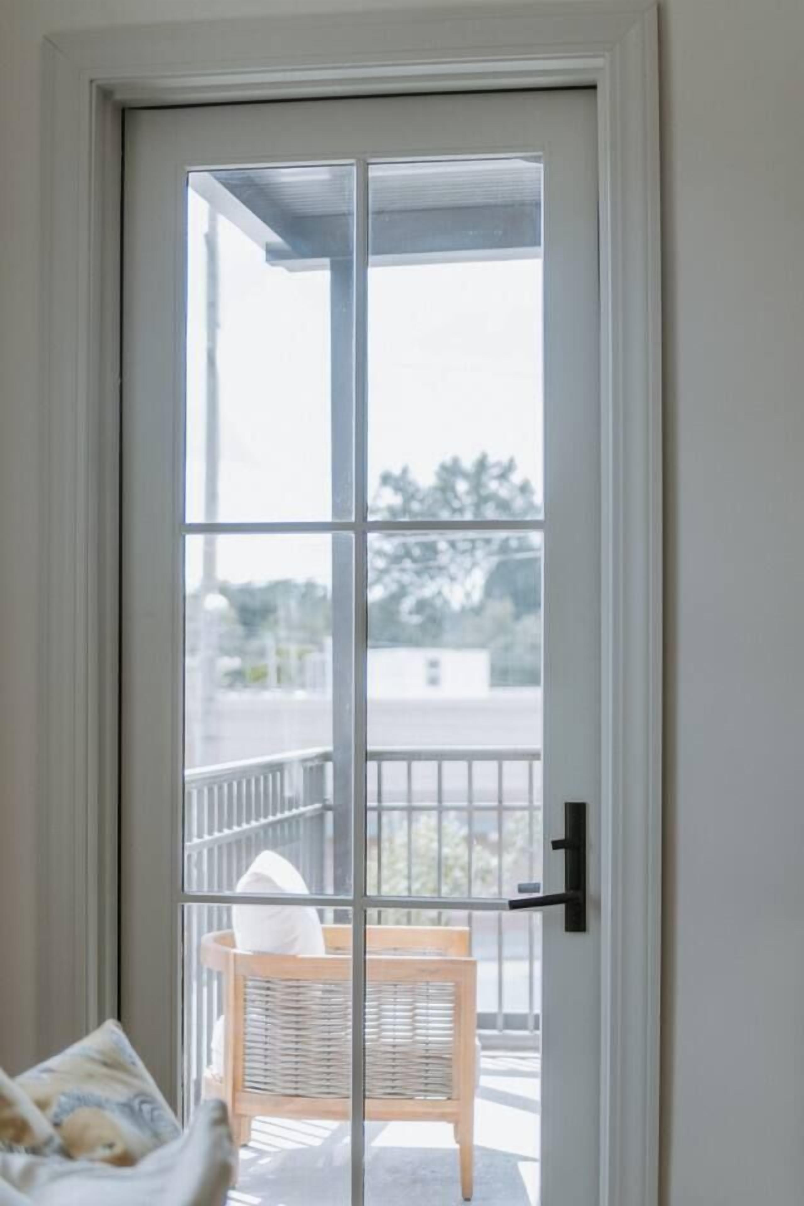 A sliding glass door leading to a balcony with a wicker chair and a cushion.