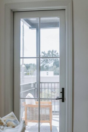 A sliding glass door leading to a balcony with a wicker chair and a cushion.