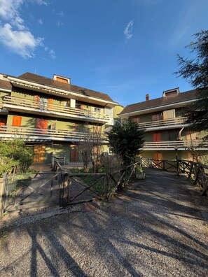 A courtyard with a gravel path, wooden fences, and buildings with balconies and windows. - Cozy mountain apartment (Altipiani di Arcinazzo)