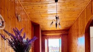 A wooden cabin interior with a bed, a table with a vase of flowers, and a view through a window. - Cozy mountain apartment (Altipiani di Arcinazzo)