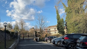 A parking area with multiple cars, a stone wall, and a clear sky. - Cozy mountain apartment (Altipiani di Arcinazzo)