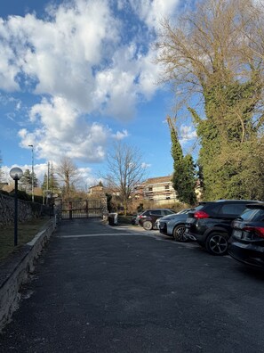 A parking area with multiple cars, a stone wall, and a clear sky. - Cozy mountain apartment (Altipiani di Arcinazzo)