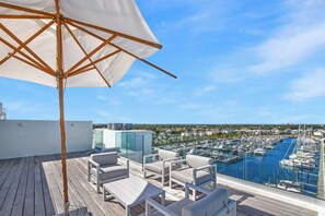 A rooftop terrace with outdoor seating and a view of a marina. - Palm Cay - 3BR Beachfront Penthouse + Private Pool (Nassau)
