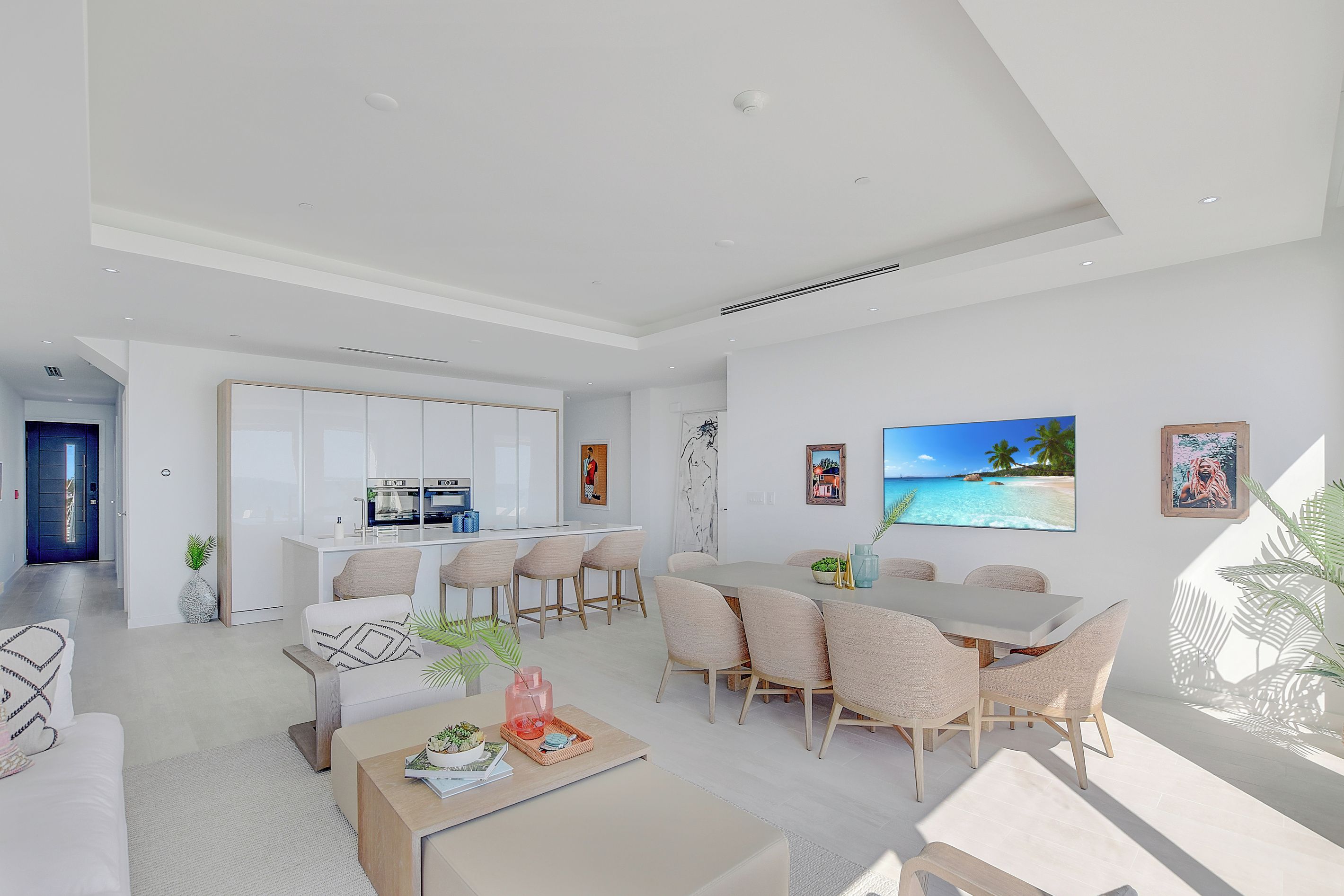 Un espace de vie moderne comprenant un coin repas, une cuisine et une grande fenêtre offrant une vue sur un paysage tropical.