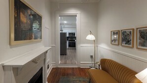 Un couloir étroit avec une cheminée, un canapé et une lampe.