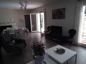 A living room with a sofa, a coffee table, and a TV. There is a door leading to another room.