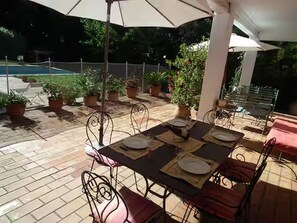 An outdoor patio with tables and chairs, surrounded by potted plants.