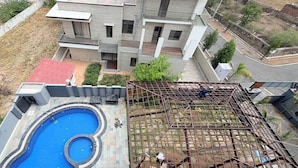 A modern multi-story building with a swimming pool and a construction site. - Tiger Hills Ridhira Retreats (Udaipur)