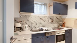 Moderni keittiö, jossa on marmoripintainen välitila, sisäänrakennettu uuni ja kahvinkeitin.