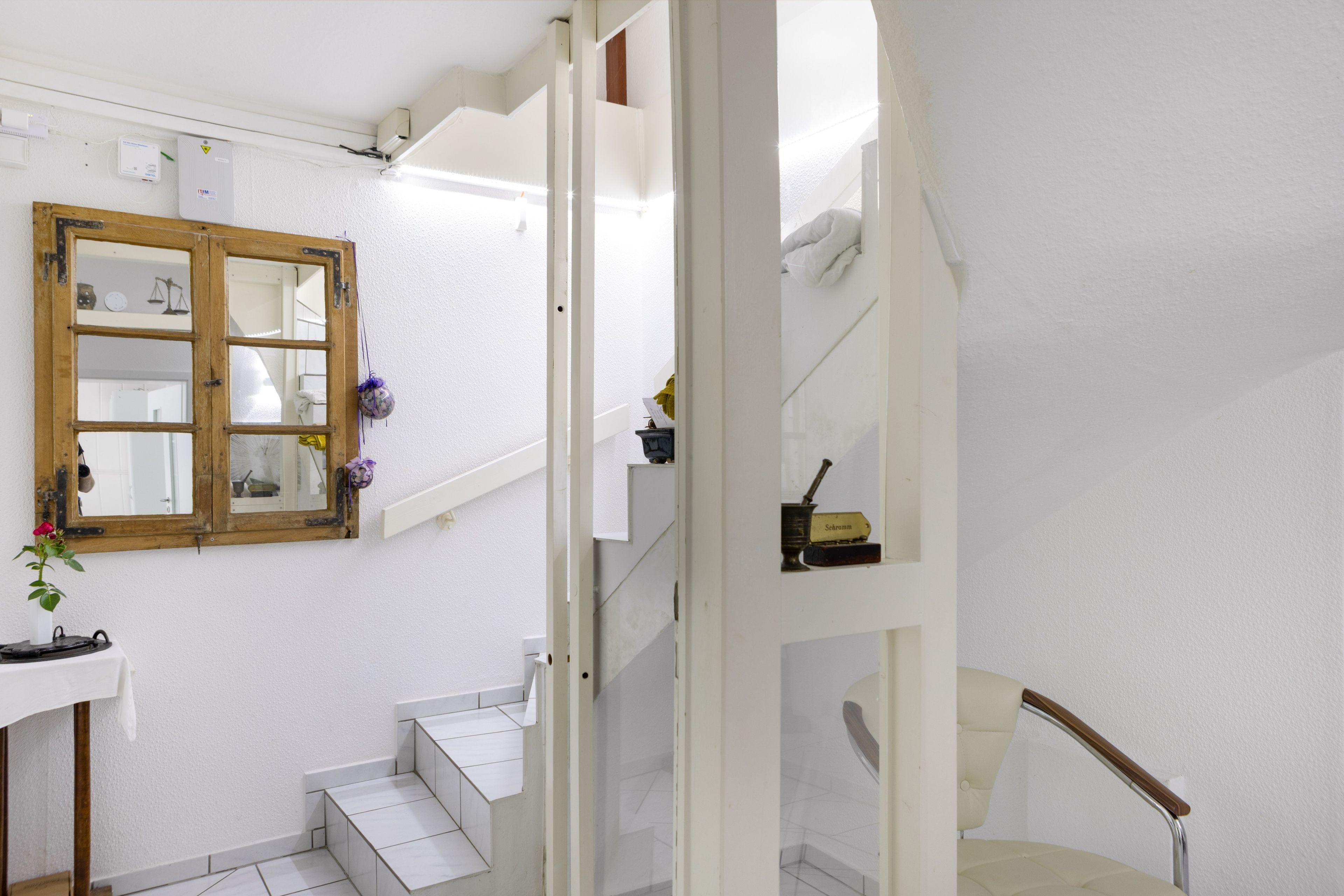 A staircase with white walls and a wooden door with a mirror.