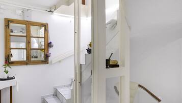 A staircase with white walls and a wooden door with a mirror.