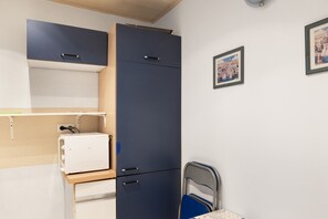 Et lille værelse med seng, skrivebord og garderobe.