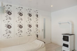Una habitación con un sofá blanco, una puerta con panel de vidrio y un mueble blanco con cajones.