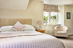 A bedroom with a bed, a bedside table with a lamp, a chair, and a window with a view of buildings. - Cozy Stay Near the Fells (Ambleside)