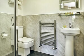 A bathroom with a toilet, a glass shower enclosure, a towel rack, a sink, and a mirror. - Cozy Stay Near the Fells (Ambleside)