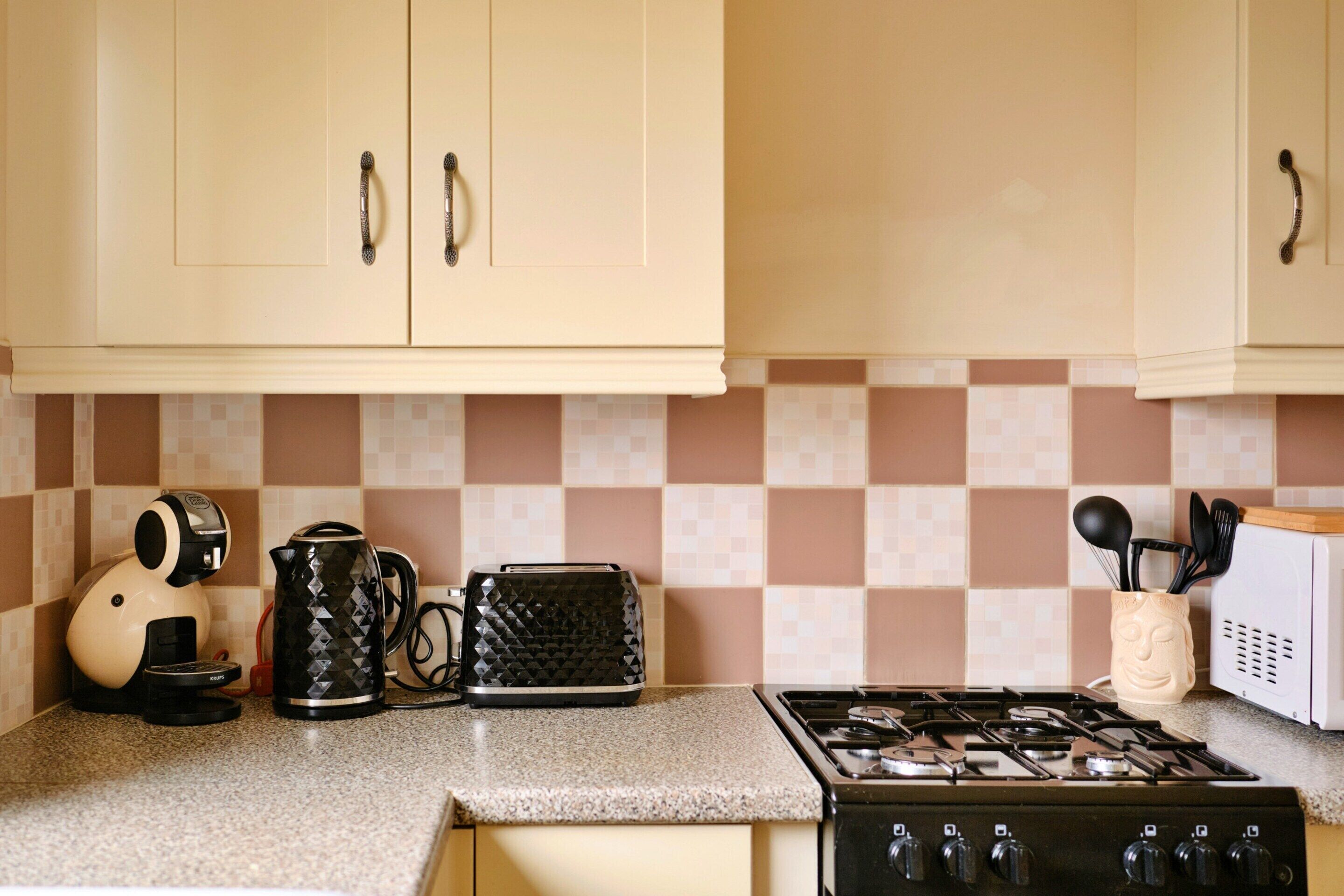 A kitchen with a gas stove, a coffee maker, a toaster, and a kettle.