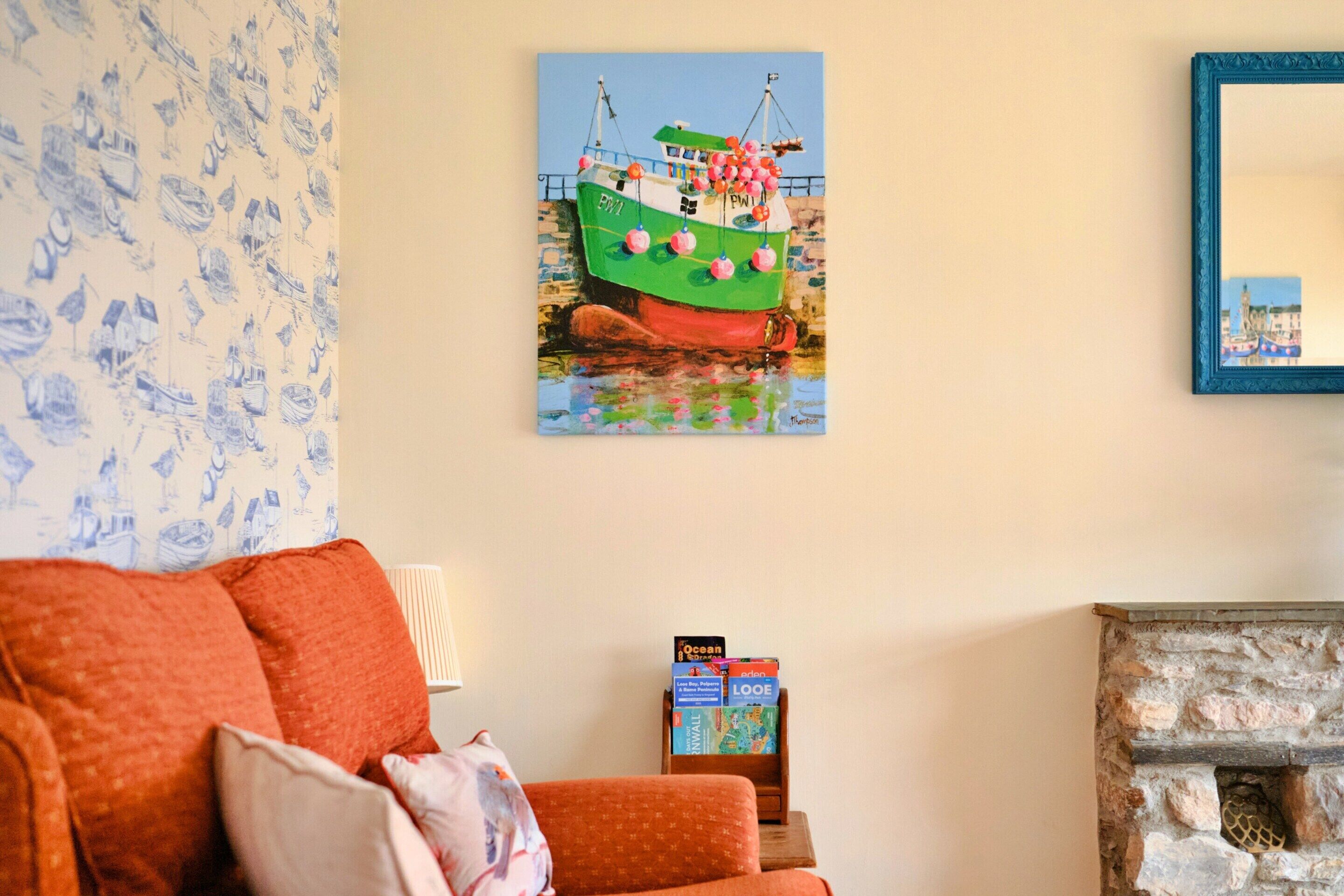 A room with a painting of a boat, a sofa, a lamp, and a fireplace.