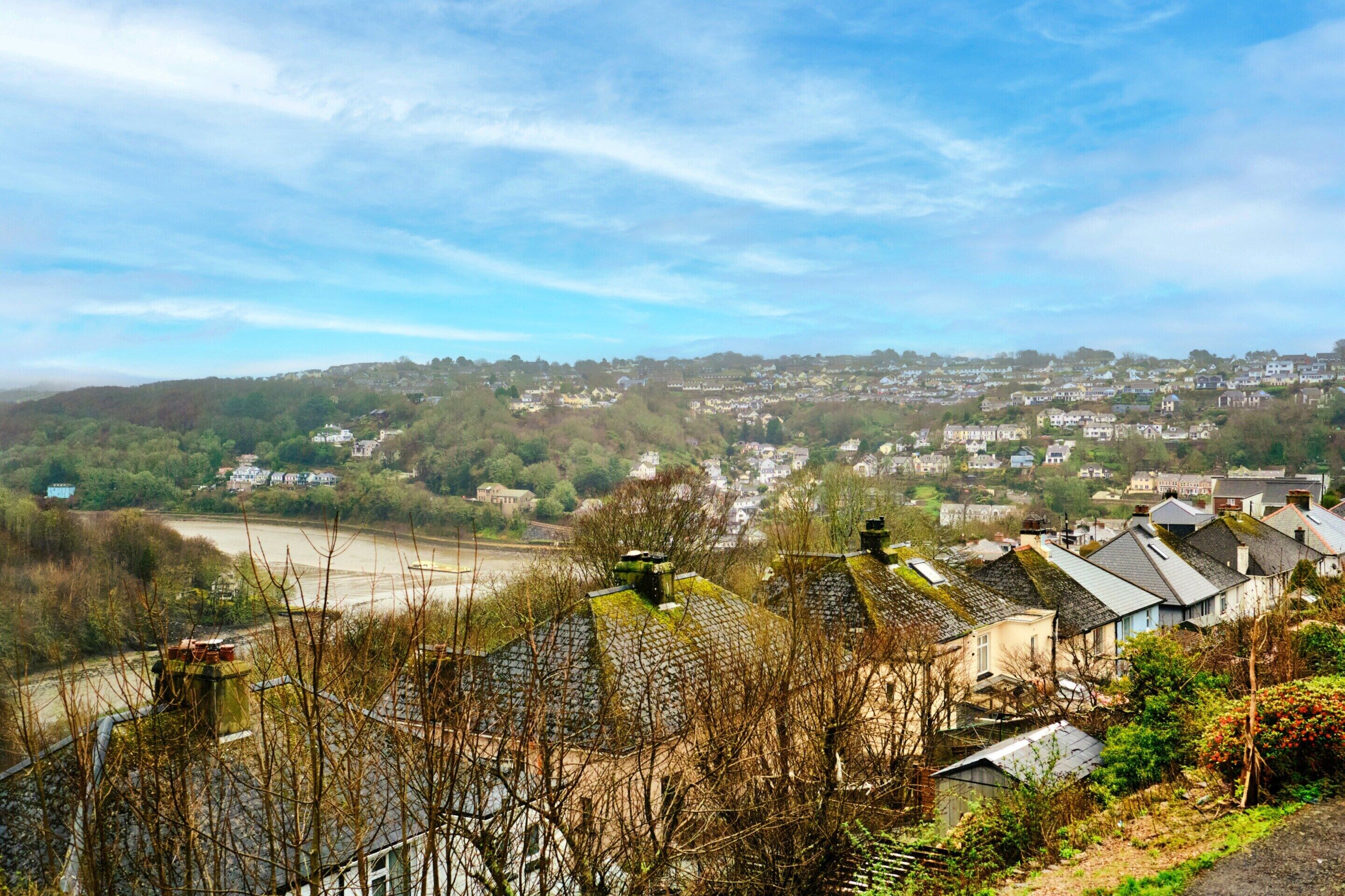 A residential area with houses, a river, and hills in the background.