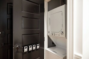 Una puerta con cerradura de seguridad y teclado numérico, y un electrodoméstico blanco, posiblemente una lavadora y secadora, en una habitación.