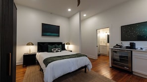 Un dormitorio moderno con cama, mesitas de noche, cómoda y televisor.