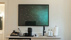 Una cucina compatta con forno integrato, macchina del caffè e lavello.