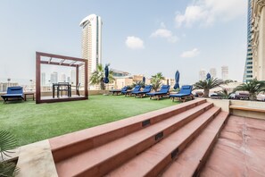 Terraza en la azotea con mesa de billar, sillones de descanso y vistas a edificios altos.