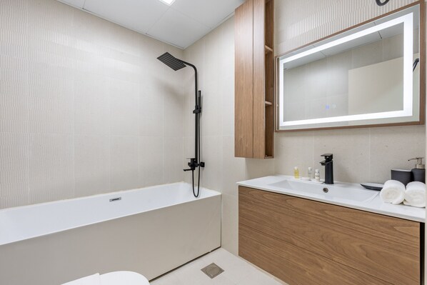 Ein modernes Badezimmer mit freistehender Badewanne, einem Holzwaschtisch mit Spiegel und einer Duschbrause.