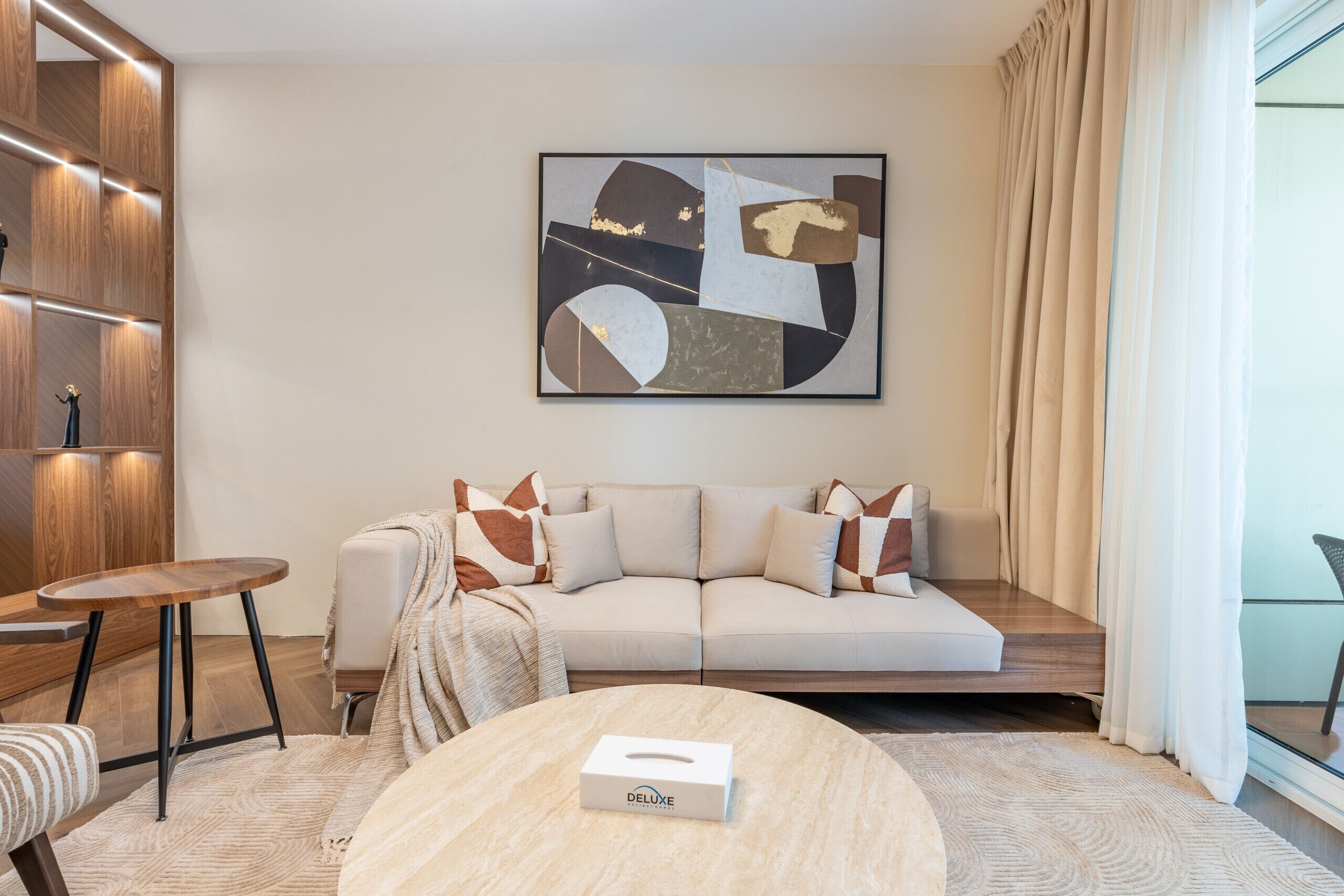 A modern living room with a sofa, a round coffee table, and a painting on the wall.