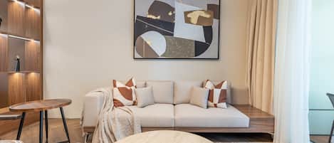 A modern living room with a sofa, a round coffee table, and a painting on the wall.