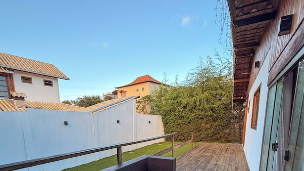 A wooden deck with outdoor furniture and a glass door leading to a covered area. - Chalé Bello in Pedra Azul (Venda Nova do Imigrante)