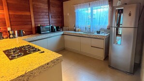 A kitchen with a granite countertop, stainless steel appliances, and wooden ceiling. - Chalé Bello in Pedra Azul (Venda Nova do Imigrante)