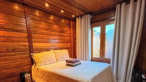 A wooden-paneled room with a bed, a fan, and a window with curtains. - Chalé Bello in Pedra Azul (Venda Nova do Imigrante)
