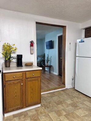 Una cocina con armarios de madera, un refrigerador blanco y una cafetera sobre la encimera.