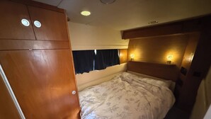 A compact bedroom with a bed, wooden wardrobe, and bedside lamps.