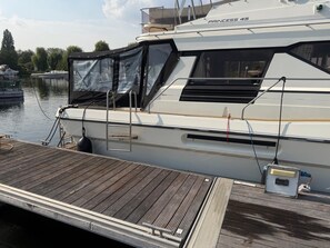 En hvid sejlbåd, der hedder 'PRINCESS 45', ligger til kaj ved en træbro.