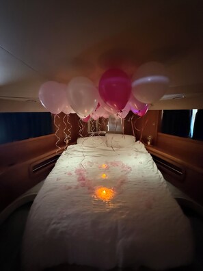 A bed with a floral bedspread, a bedside table, and a headboard.