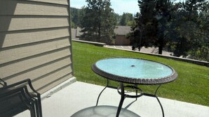A patio with a round table and a chair, a grassy lawn, and a house in the background. - Bigfork Harbor Retreat (Bigfork)